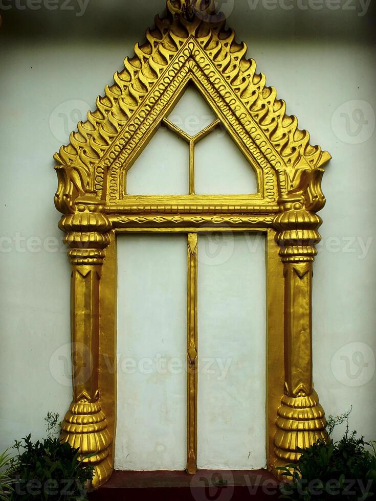 Gold framed archway with a window in the middle. The archway is ornate and has a triangular shape photo