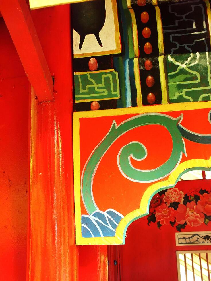 Traditional Classic and Ethnic wooden wall with red and green spiral design. The wall is painted in a bright color and has a lot of detail photo