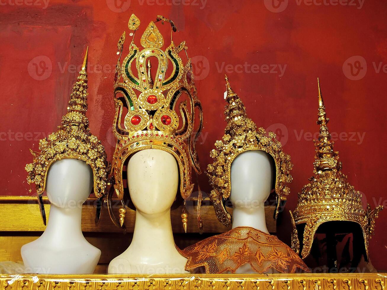 Close up view of an classic asian culture golden hats are displayed on a shelf. The hats are decorated with jewels and are arranged in a row. Concept of elegance and sophistication photo