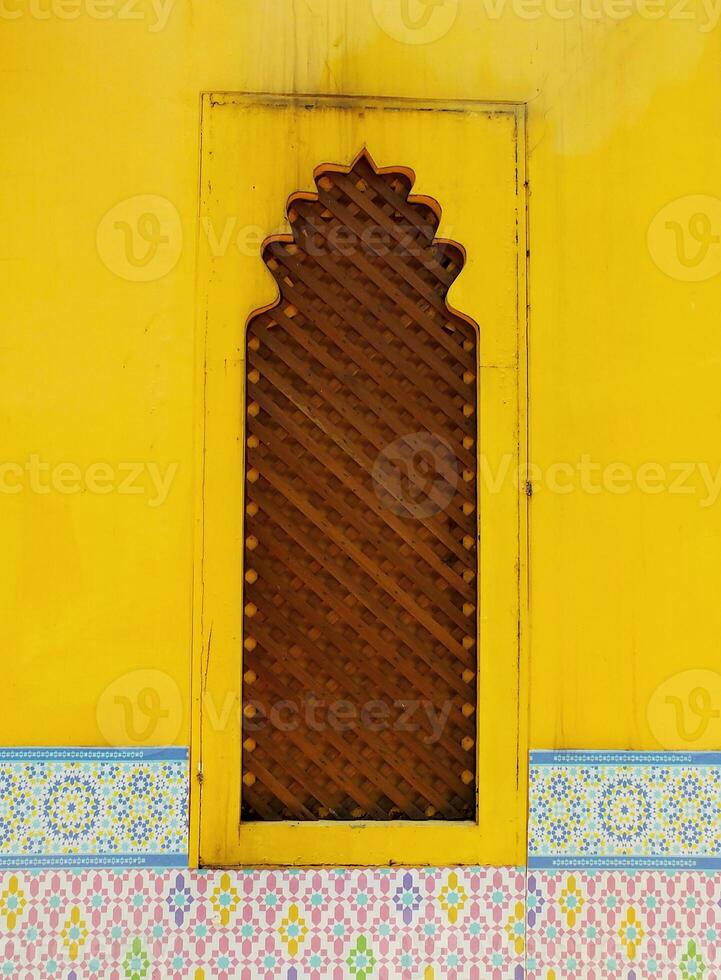 Classic traditional yellow window with a wooden frame and a lattice design. The door is open and the frame is brown. Vintage background. photo