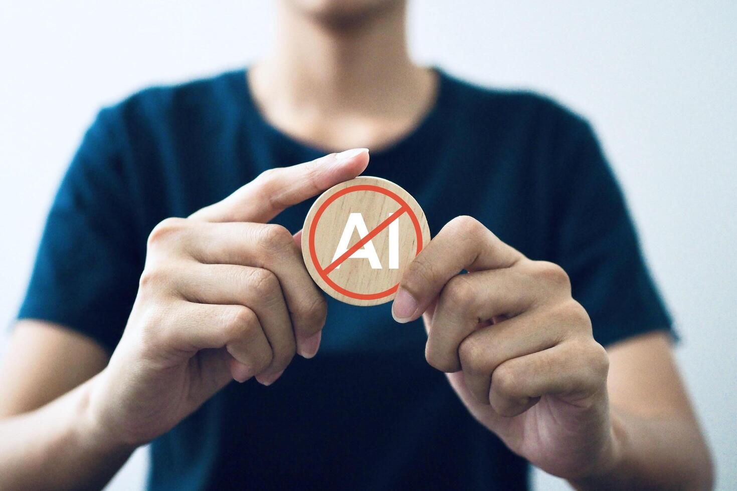 Businessman holds a wooden block against artificial intelligence and shows a no ai sign. photo