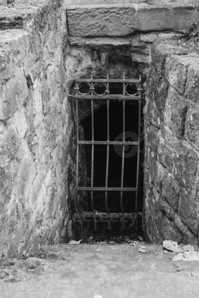 Historic stone entrance with barred gate leading into dark passage in quiet area photo