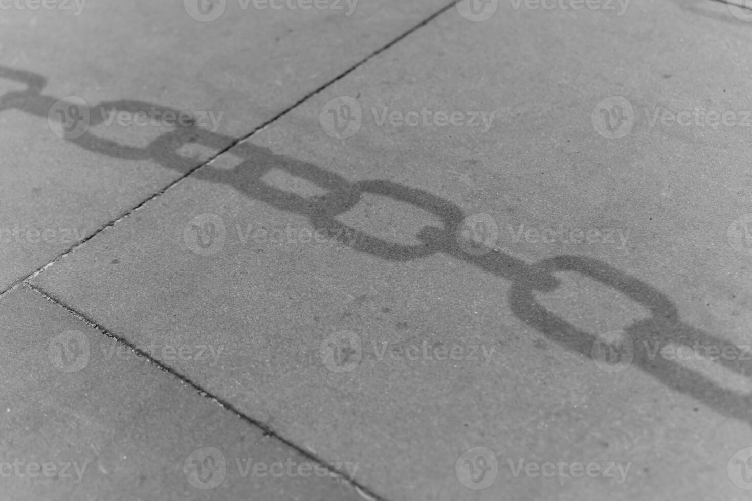 Shadows of a chain on concrete surface revealing a connection to the past in an urban environment photo