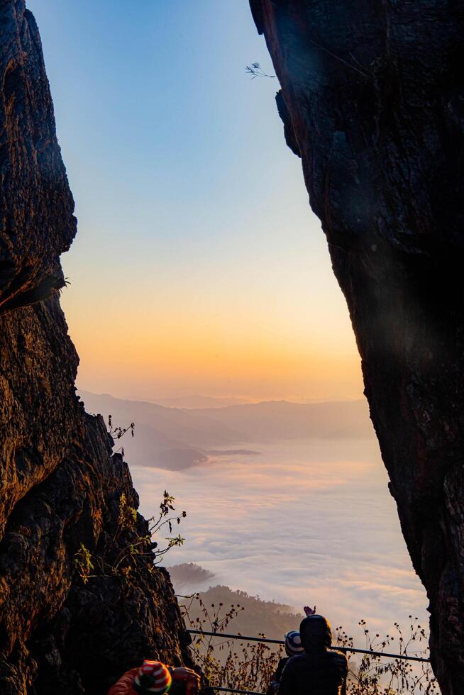 The cliff shows the fog as the sun rises over the golden sky in the background. Forest Park, Thailand. Rainforest. Bird's eye view. photo