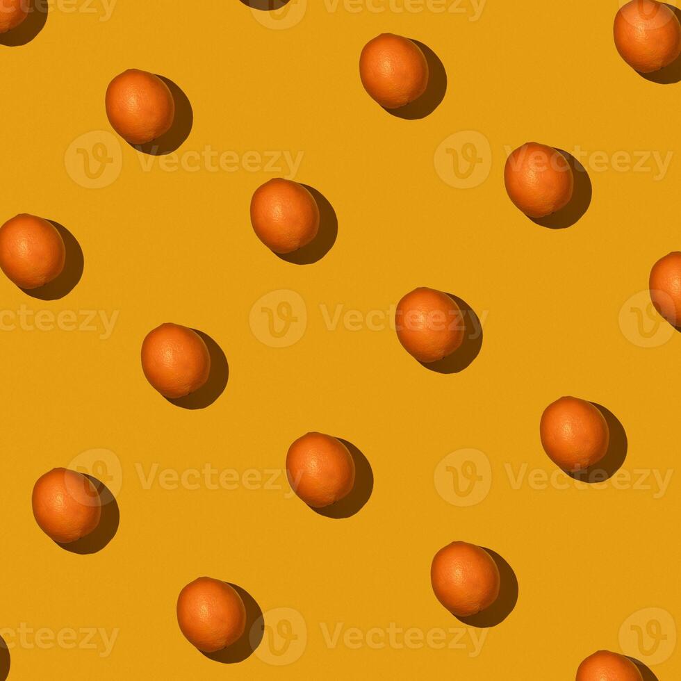 Fresh juicy whole orange on yellow background. Fruit pattern, summer concept. Flat lay Top view. Background with citrus fruits photo