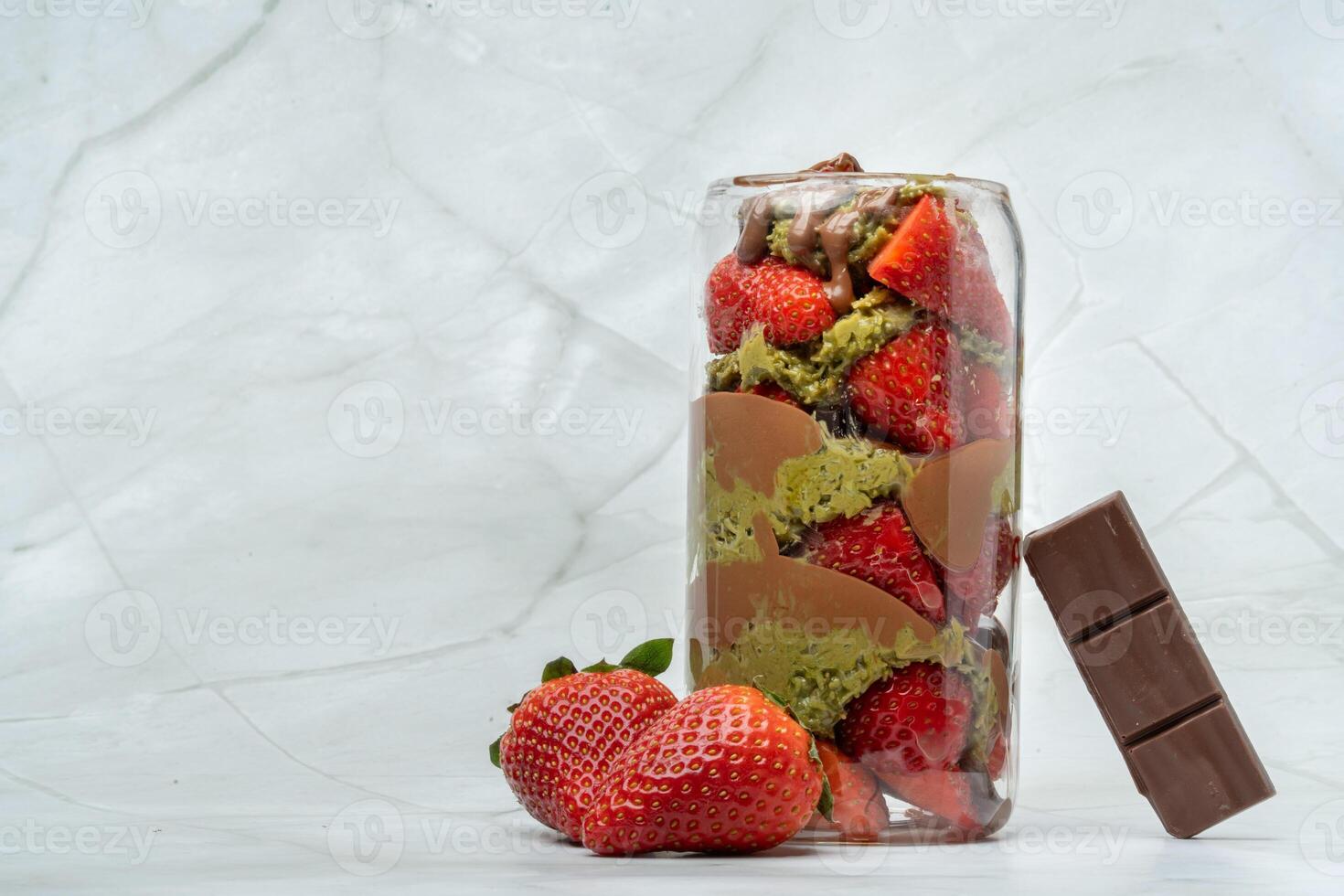 Dubai chocolate strawberry cup with kataifi, pistachio paste, tahini, milk chocolate and fresh strawberries. Decorated with strawberries and chocolate bar piece. Copy space for text. photo