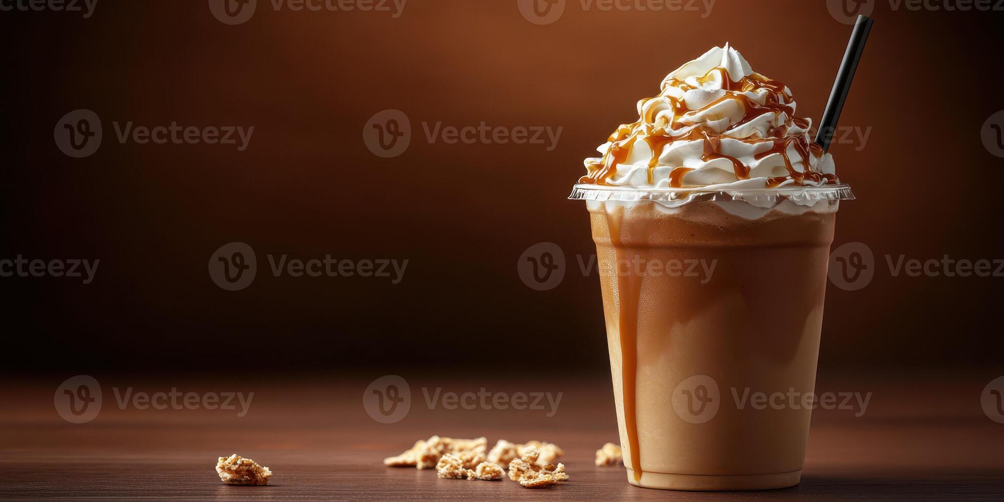 Creamy caramel frappuccino topped with whipped cream and drizzle served in a clear cup on a wooden table photo