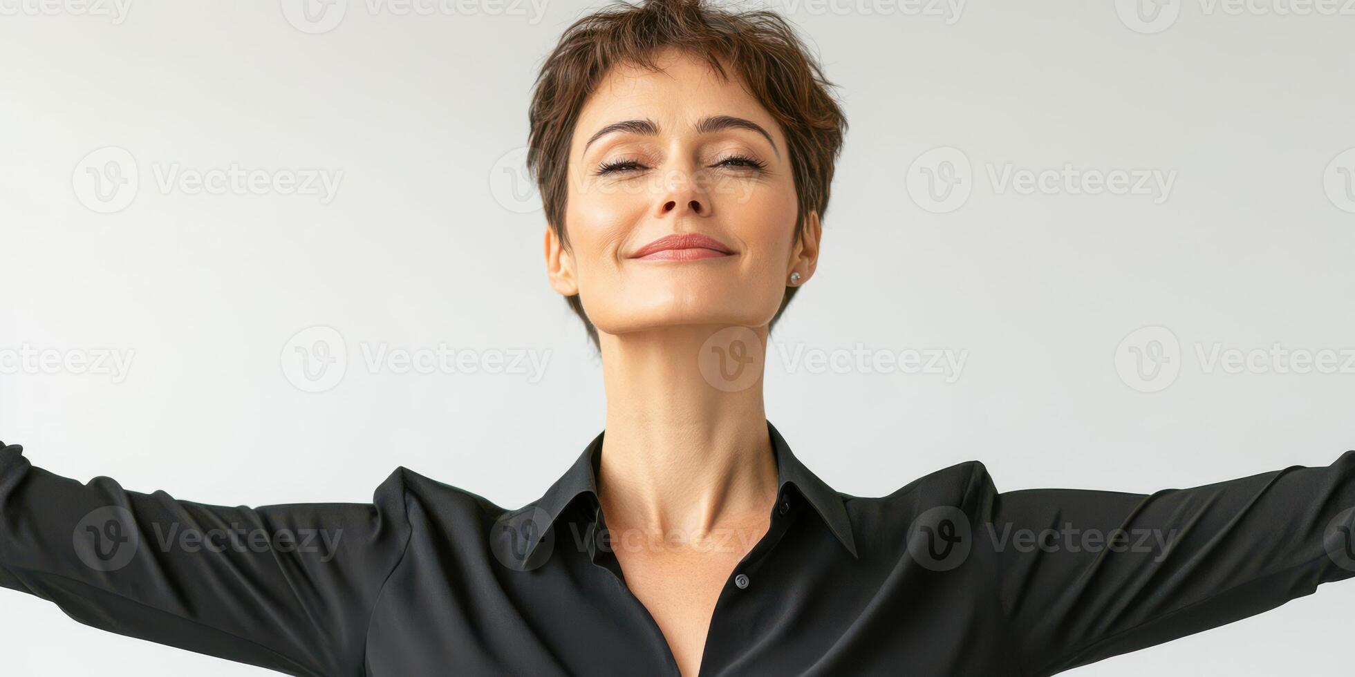 Confident woman smiling with arms outstretched against a neutral background in a studio setting photo