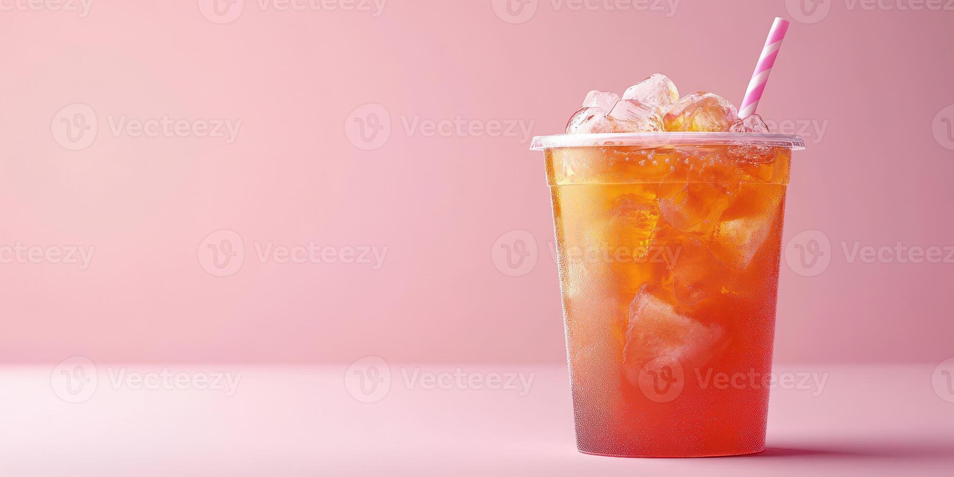 Iced tea served in a clear cup with a straw on a light pink background photo