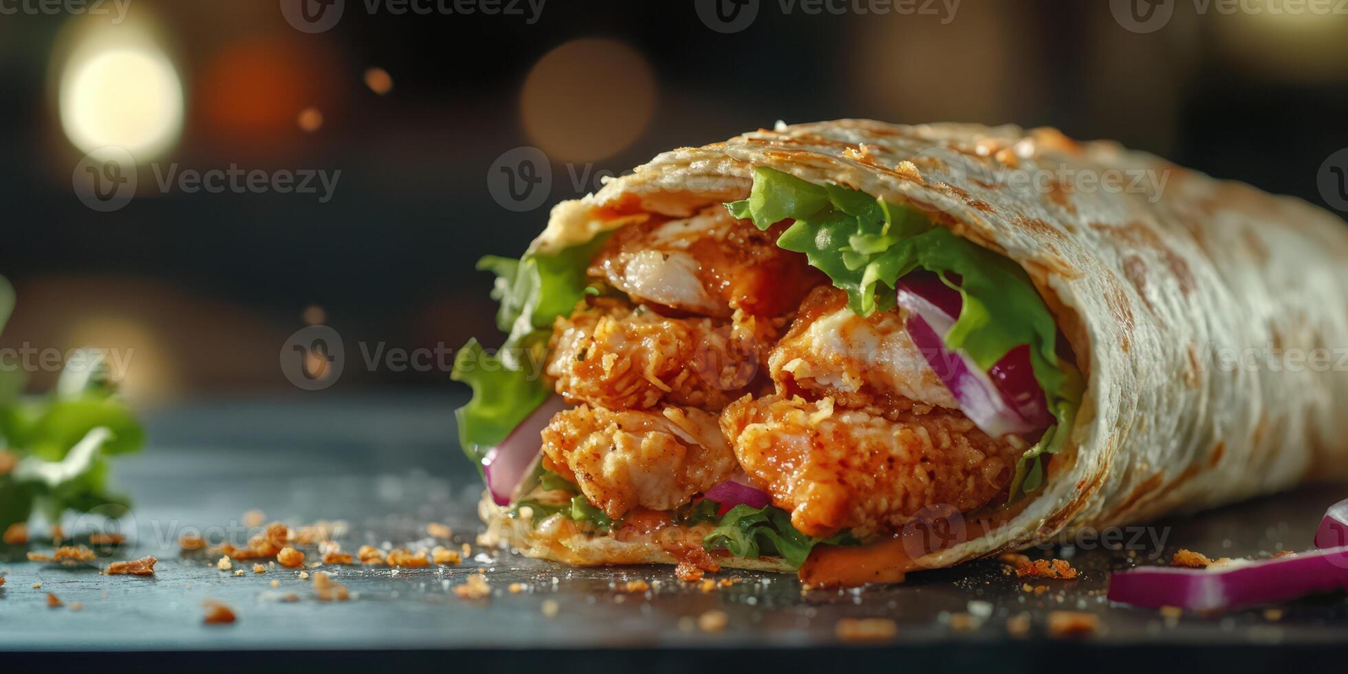Delicious wrap filled with crispy chicken, fresh vegetables, and savory sauce presented on a dark surface photo