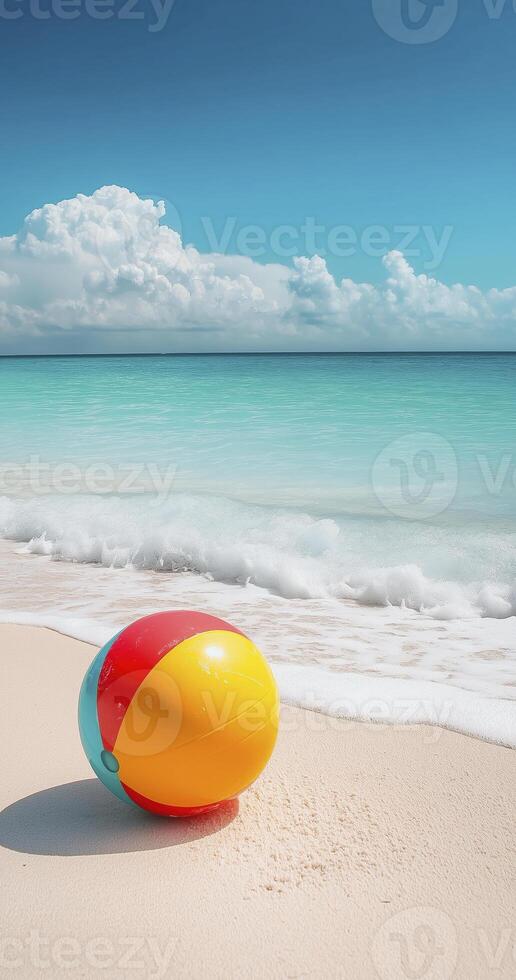 colorful beach ball rests on white sandy shore, with gentle waves lapping at beach under bright blue sky photo