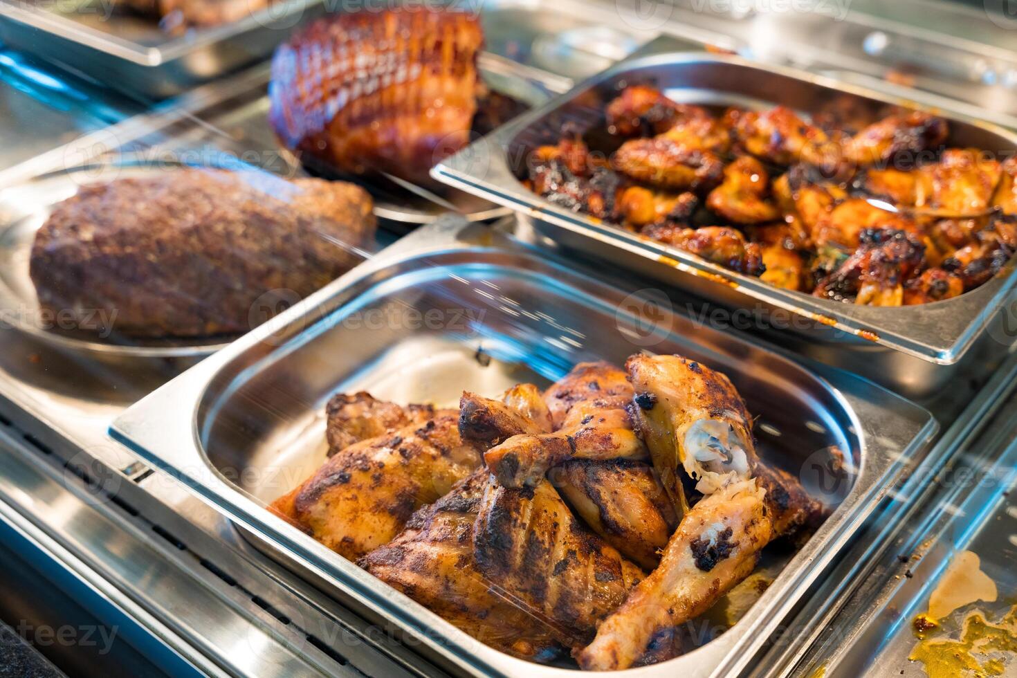 Grilled chicken drumsticks and wings in a buffet display photo