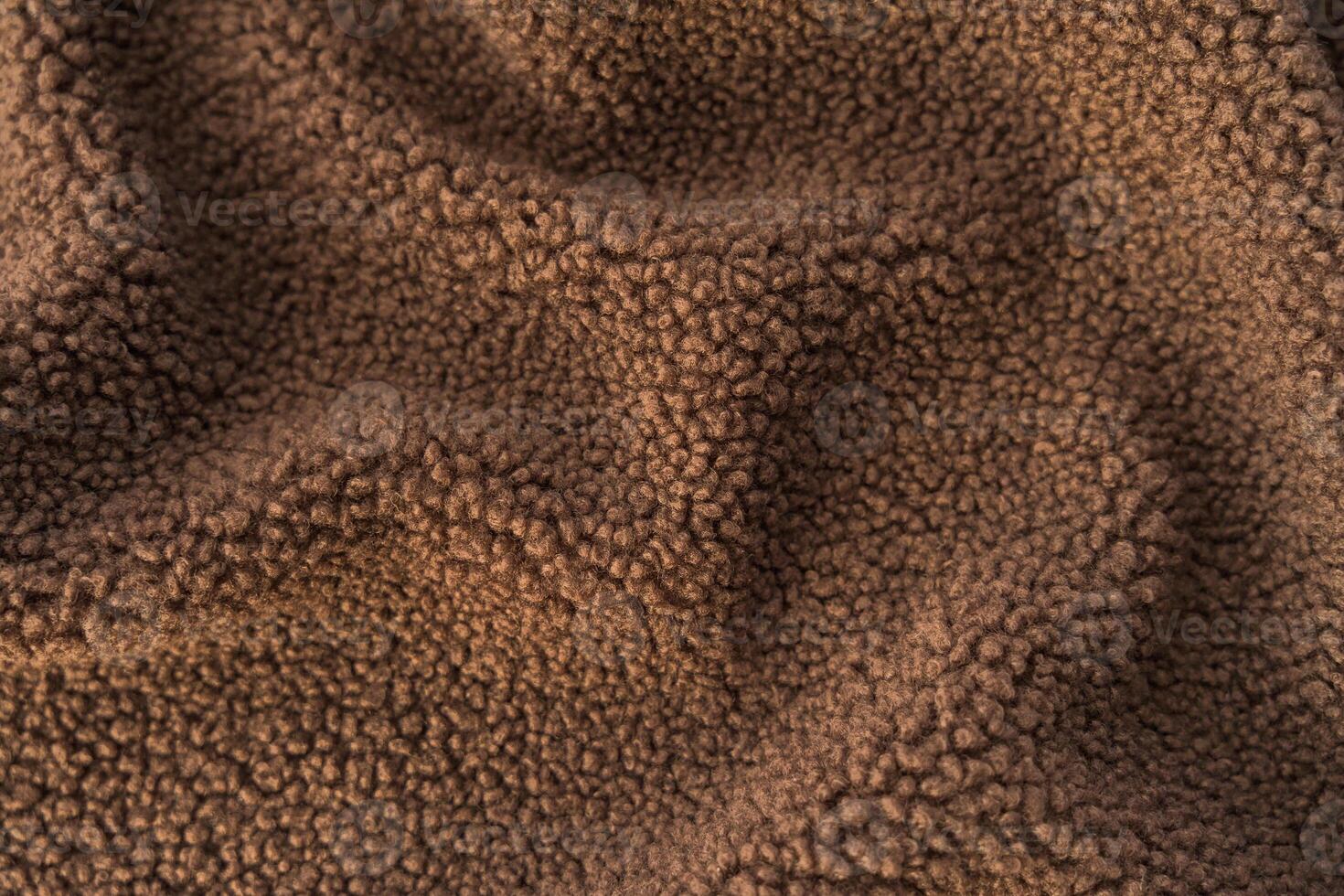Textured close-up of thick, fluffy brown teddy fleece fabric. photo