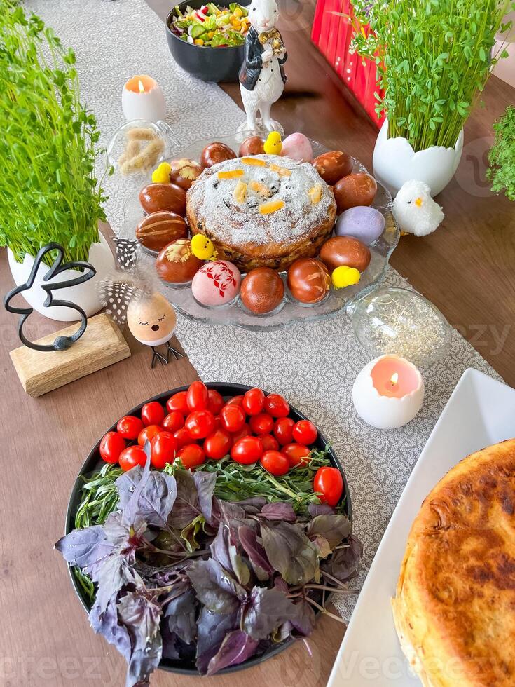 Easter festive table with traditional cake, dyed eggs, and fresh vegetables photo