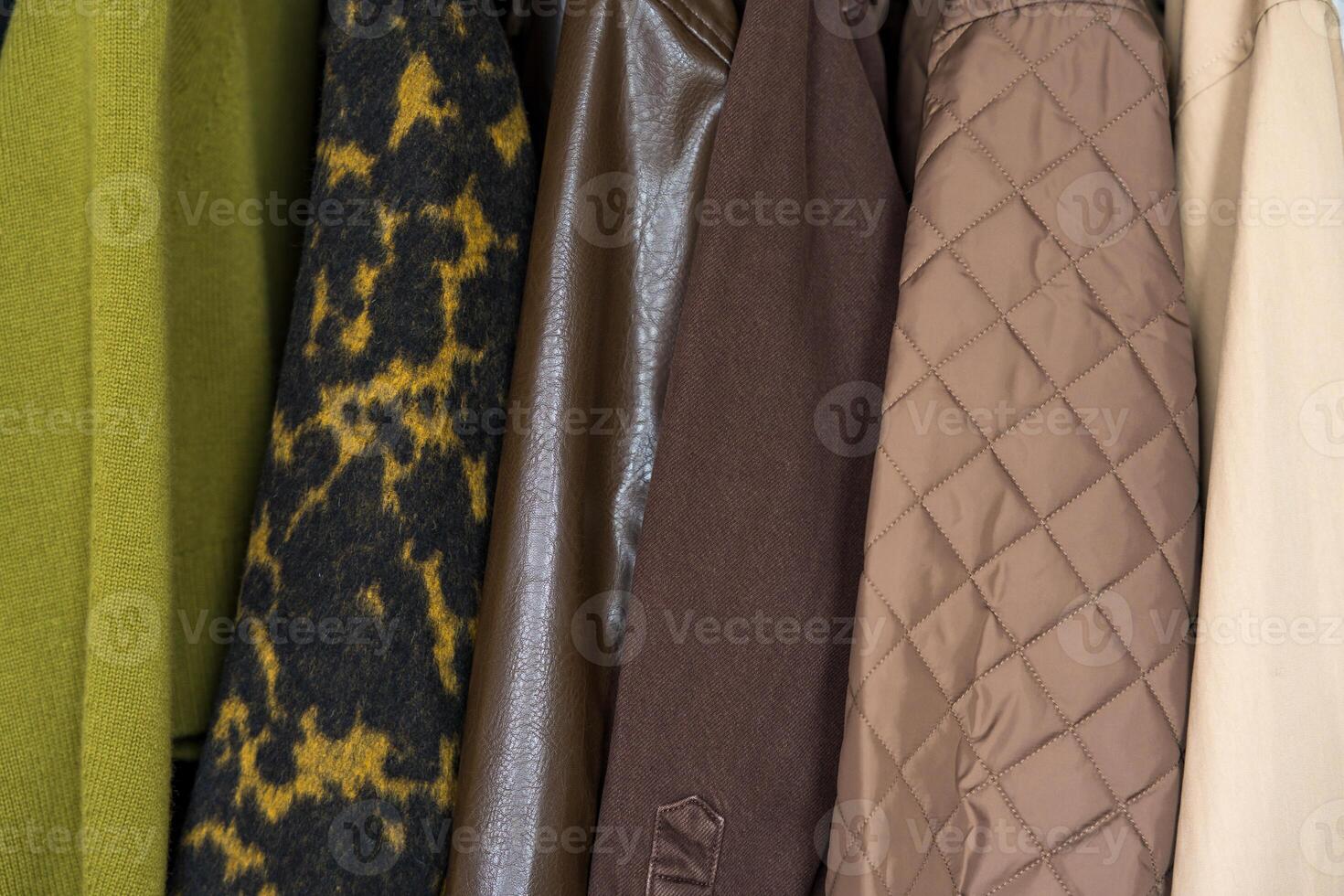 A row of autumn, winter, spring coats in earthy tones hanging on a sleek clothing rack. photo