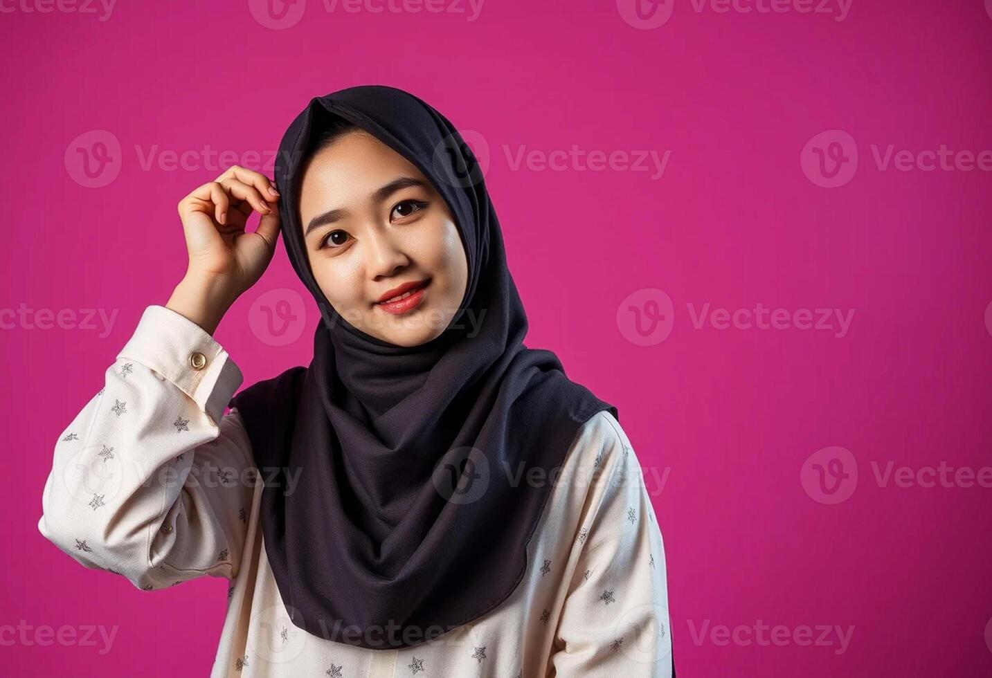 Portrait of a beautiful young muslim woman wearing hijab on pink background photo