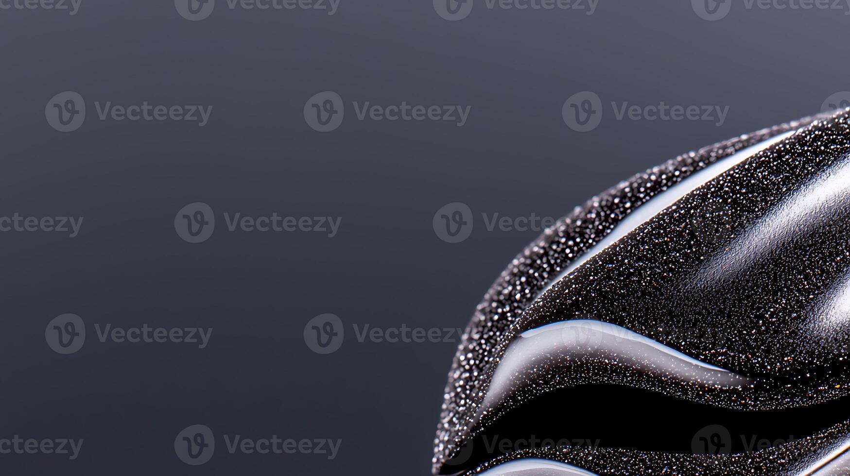 Close-up view of glossy black abstract shape against a smooth dark background, showcasing texture photo