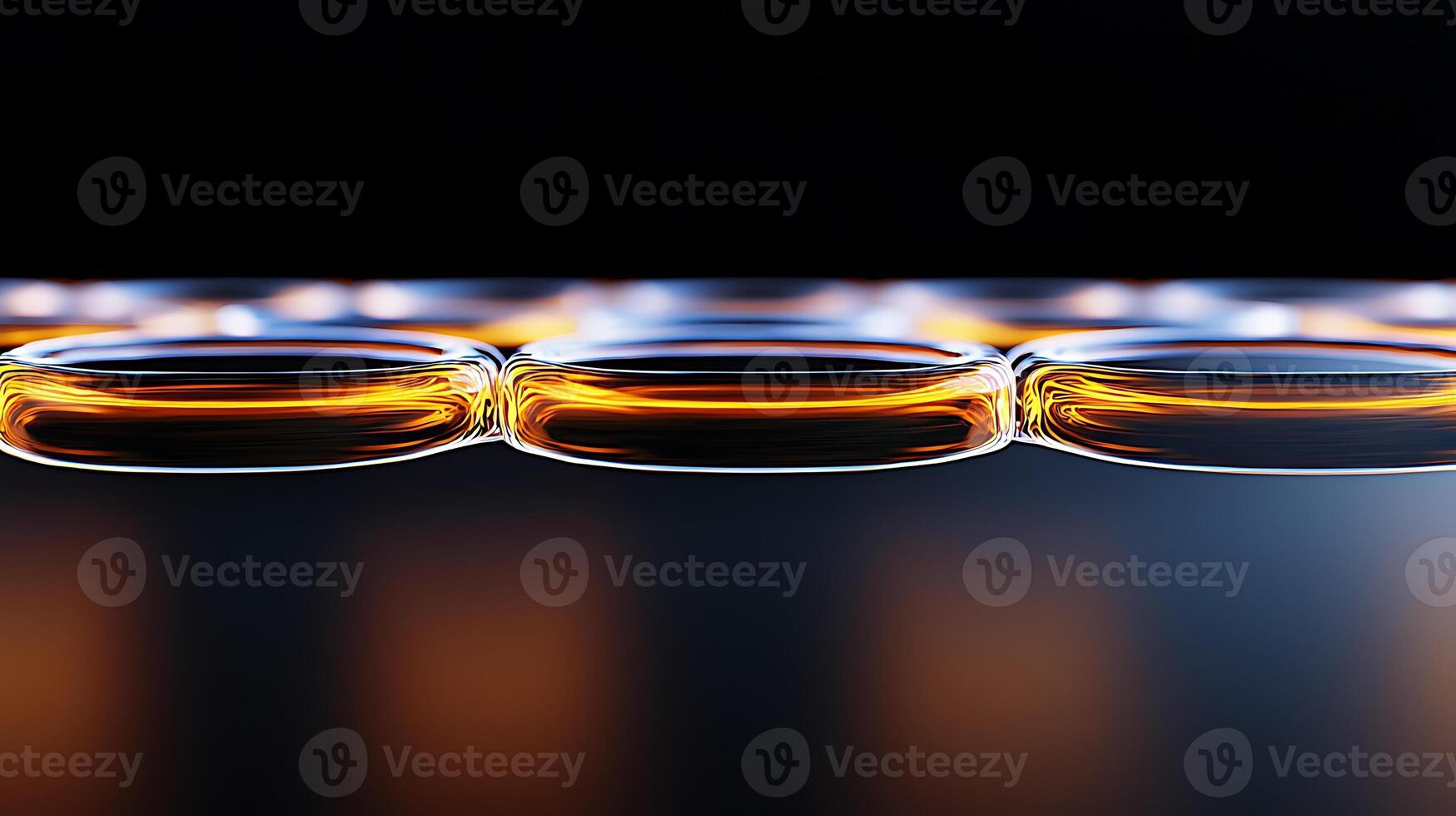 Close-up view of illuminated glass bottles filled with amber liquid against a dark background photo