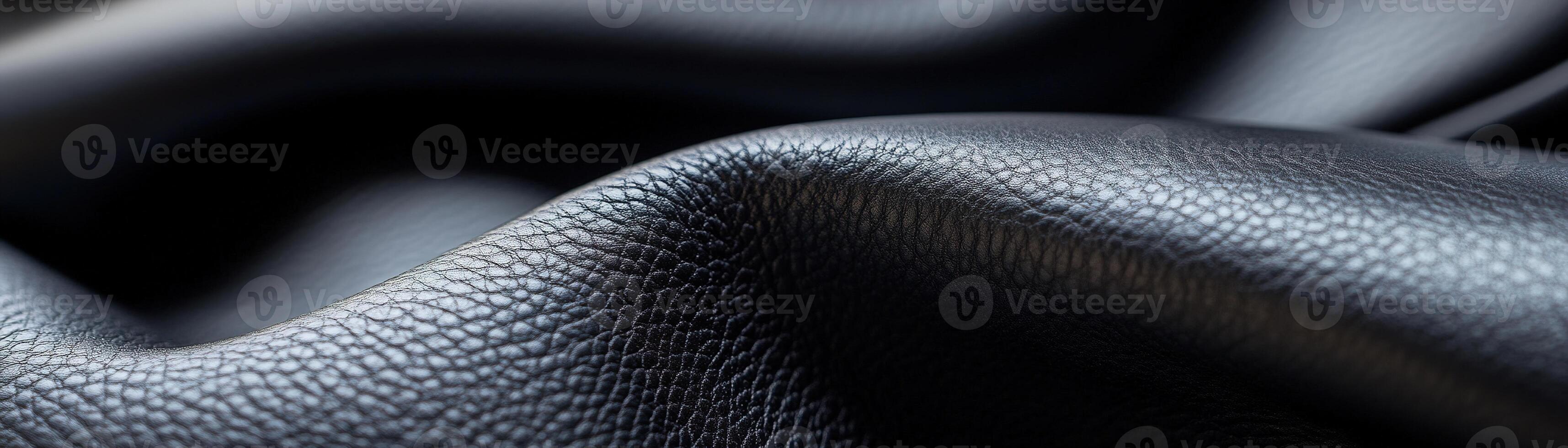 Smooth black leather displays a refined texture illuminated by diffused lighting, creating soft highlights and ample negative space ideal for luxury branding and typography photo