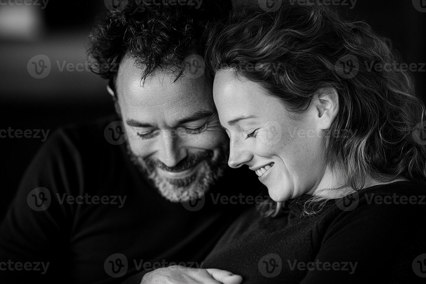 The father-to-be rests his head on the mother's belly, laughing softly as he feels the baby kick. The softly blurred background enhances their intimate connection photo