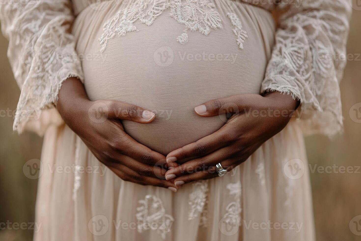 Two hands delicately hold a rounded pregnant belly, showcasing the tender bond between partners. The scene is softly blurred, emphasizing love and connection during this special moment photo