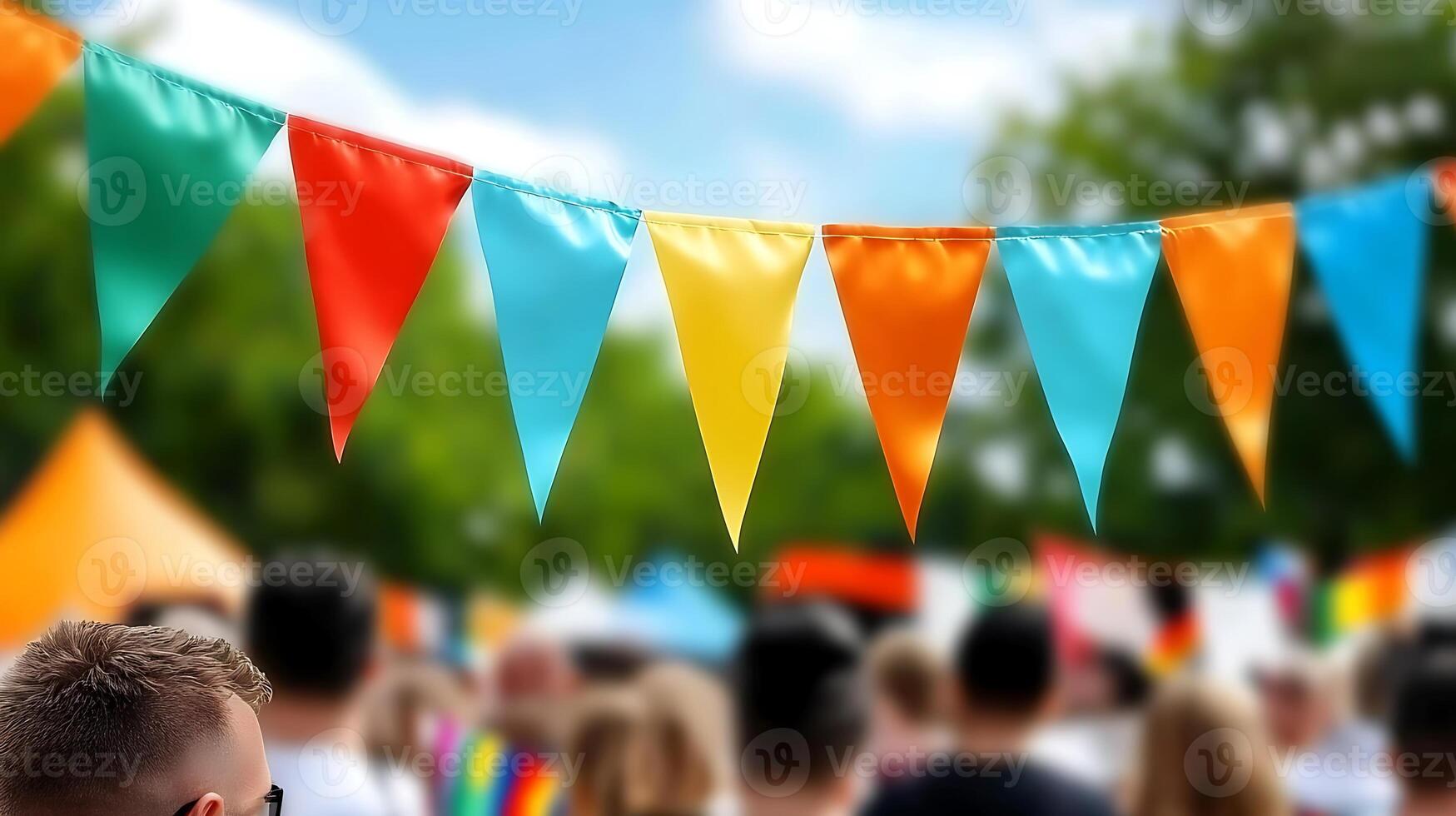 Colorful bunting flags wave above a lively outdoor festival with blurred crowd in background photo