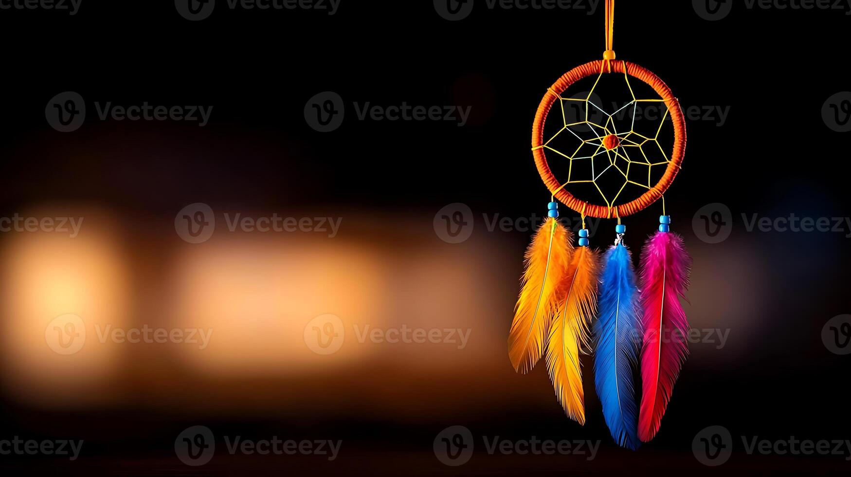 Colorful dreamcatcher with vibrant feathers hanging against a blurred dark background photo