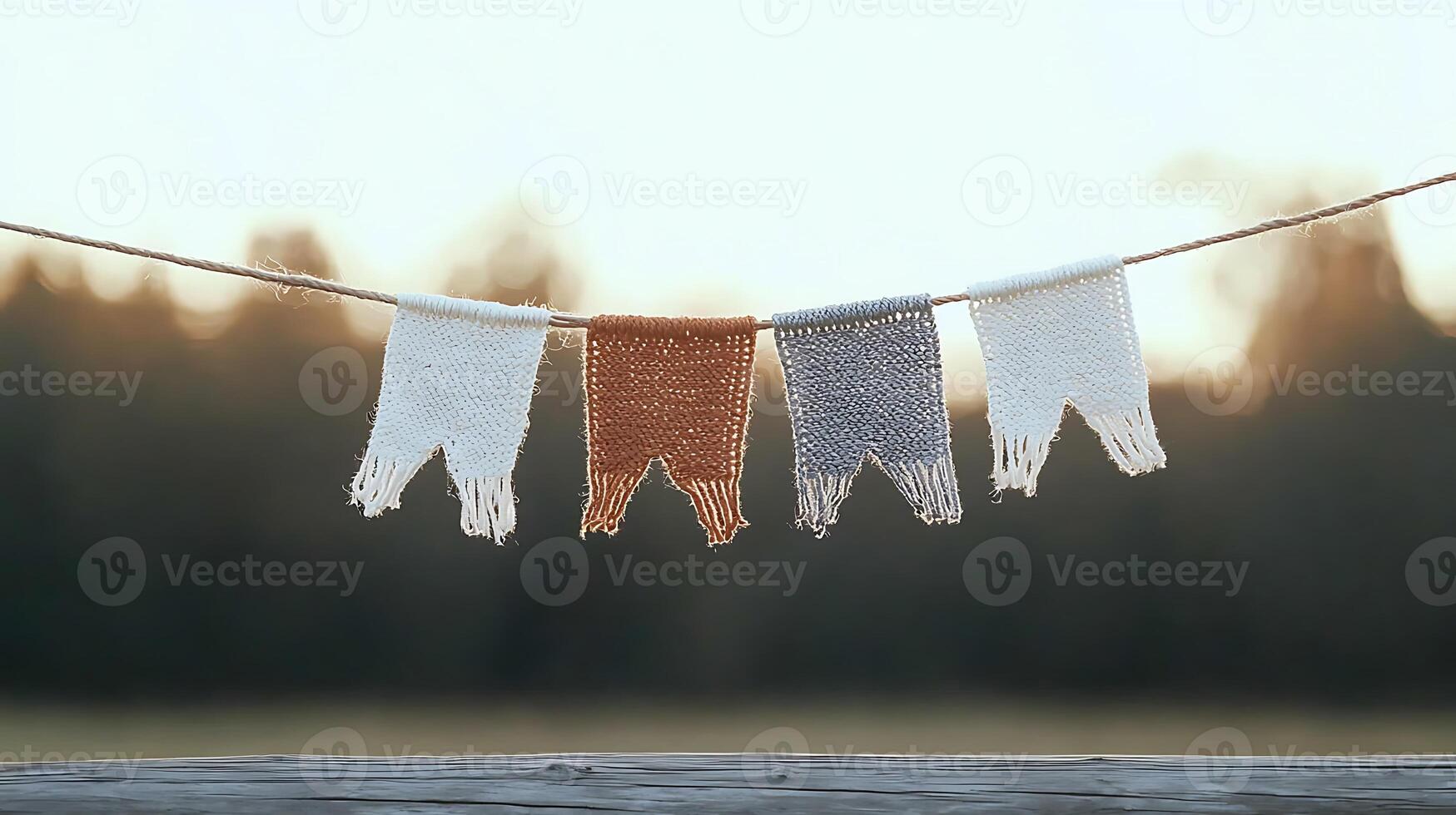 Colorful knitted banners hanging on a string against a soft sunset backdrop in nature photo
