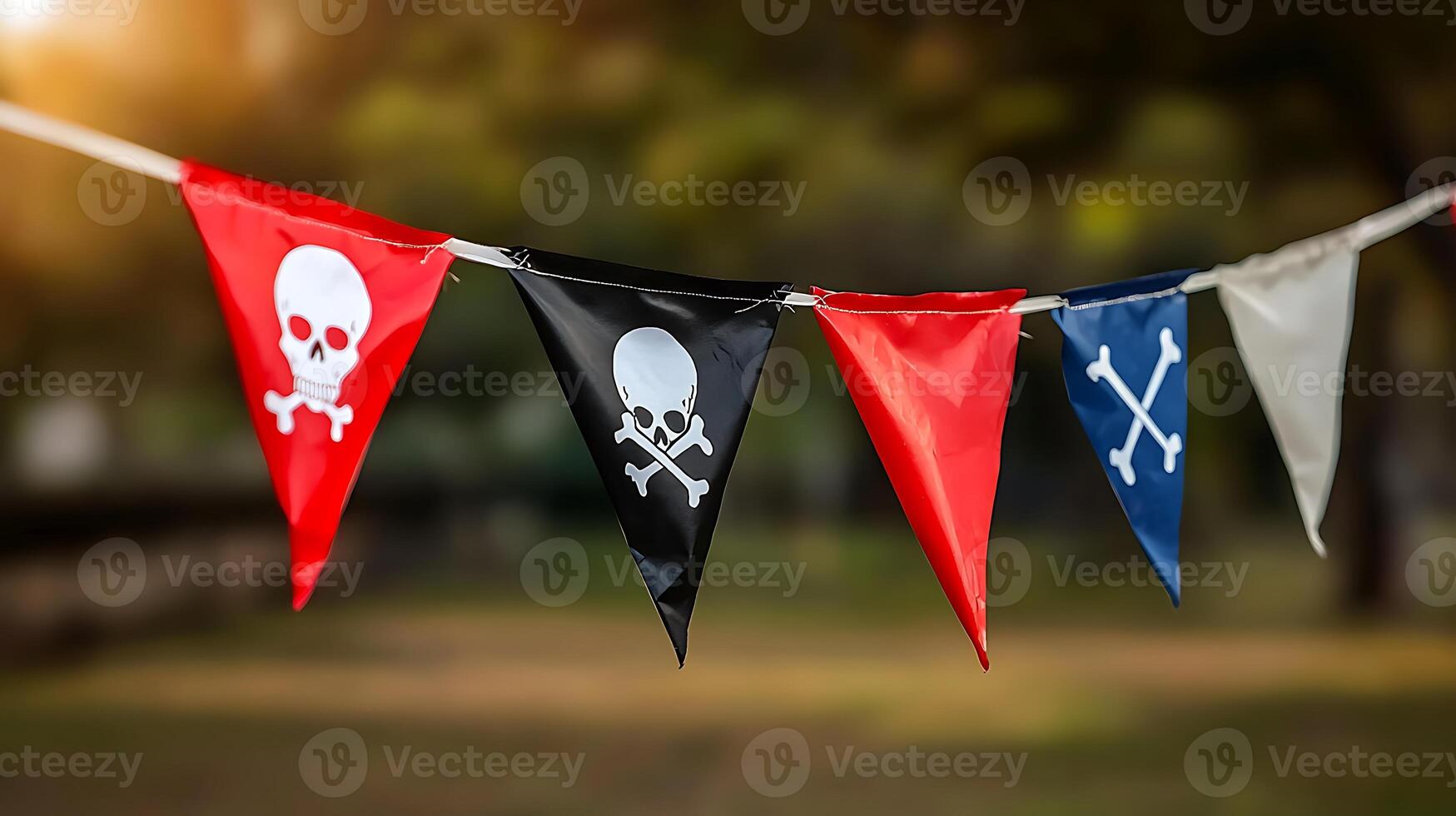 Colorful pirate-themed flags hanging outdoors against a blurred natural background photo