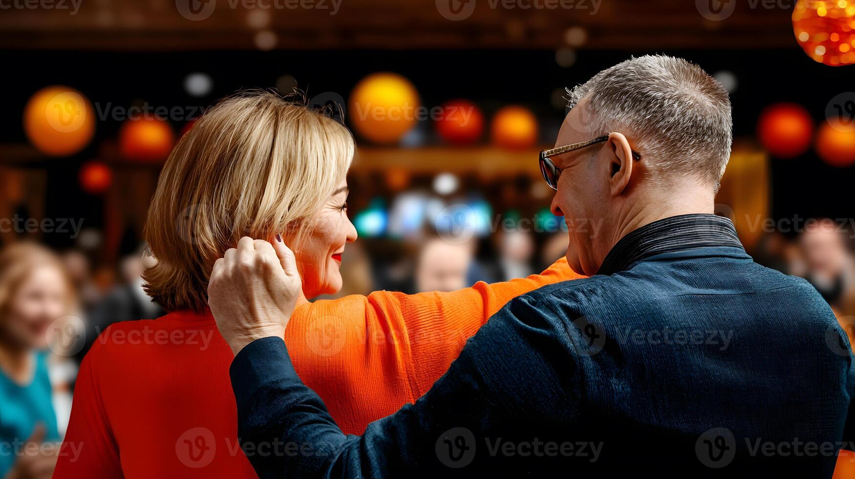Couple enjoying a joyful moment at a vibrant social gathering with colorful lights in the background photo