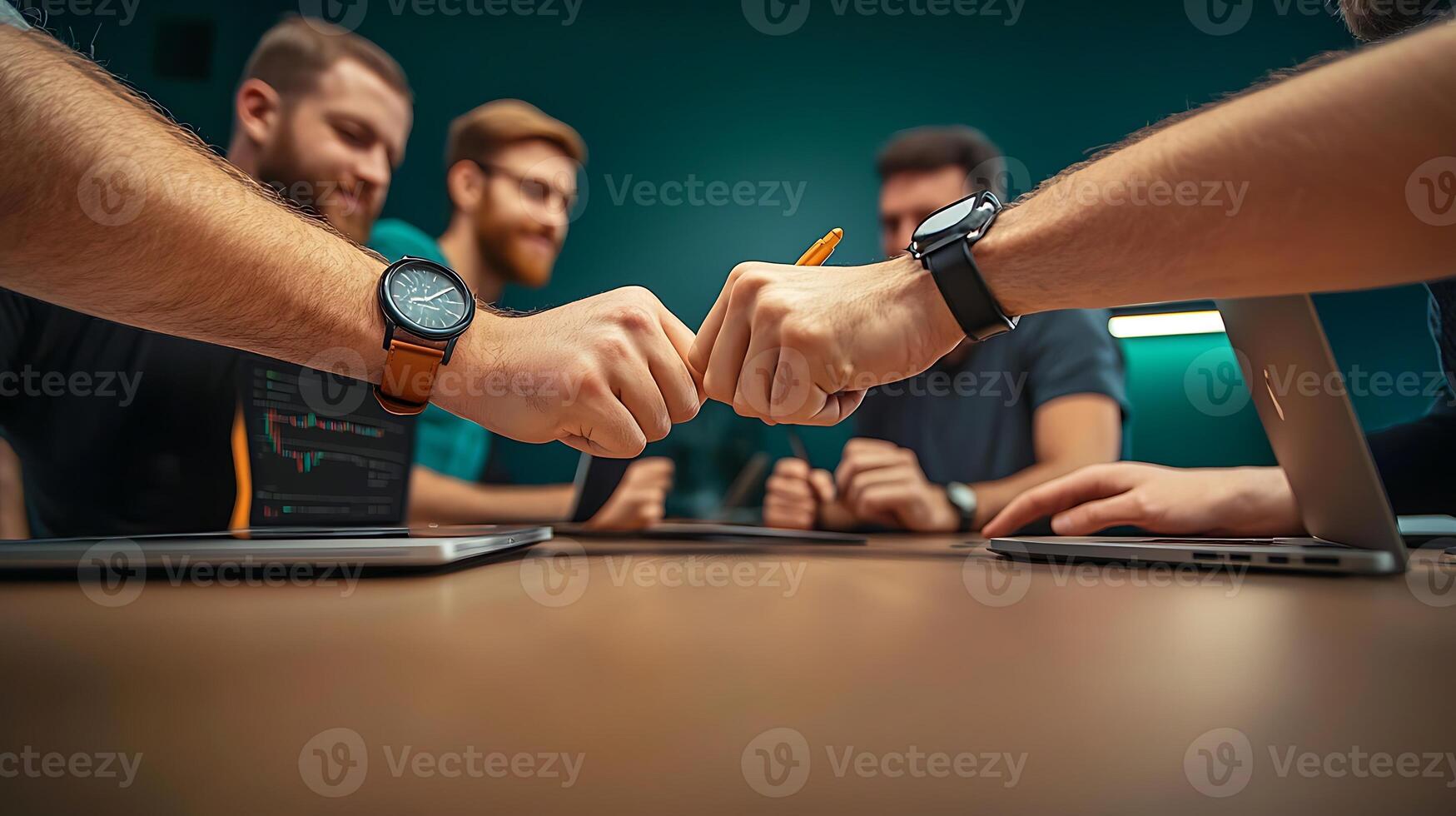 Team Collaboration Professionals Engaging in a Fist Bump Over Laptops in a Modern Office Space photo