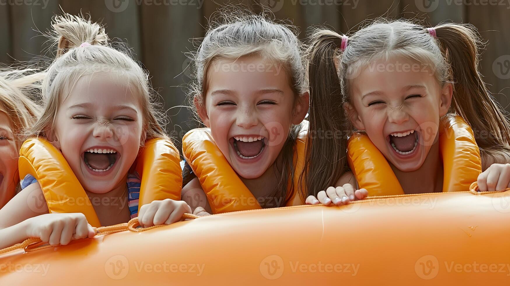 Three joyful children in life jackets laughing on an inflatable boat by the water's edge photo