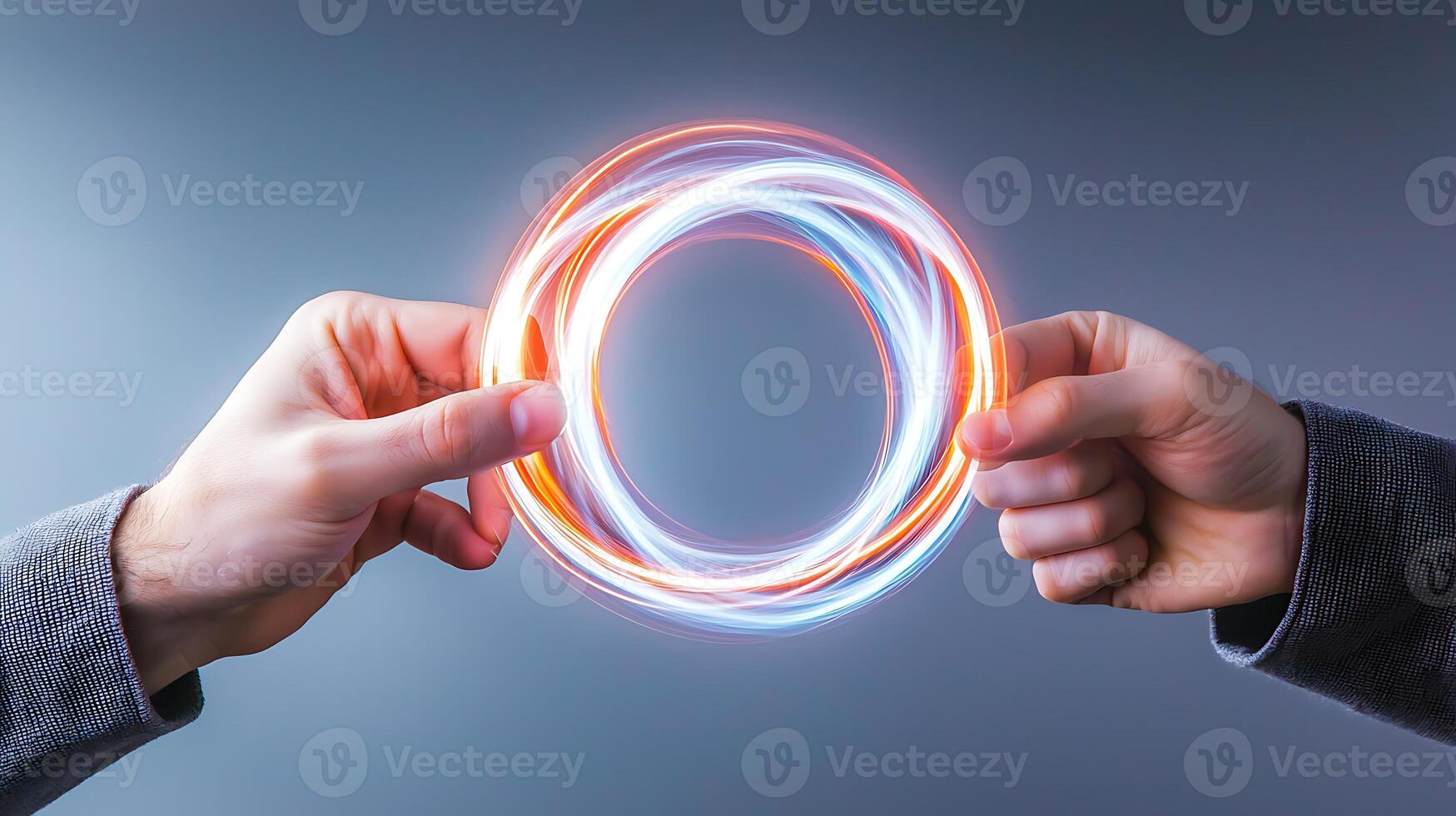 Two hands holding glowing energy rings, creating a dynamic visual effect against a gray background photo