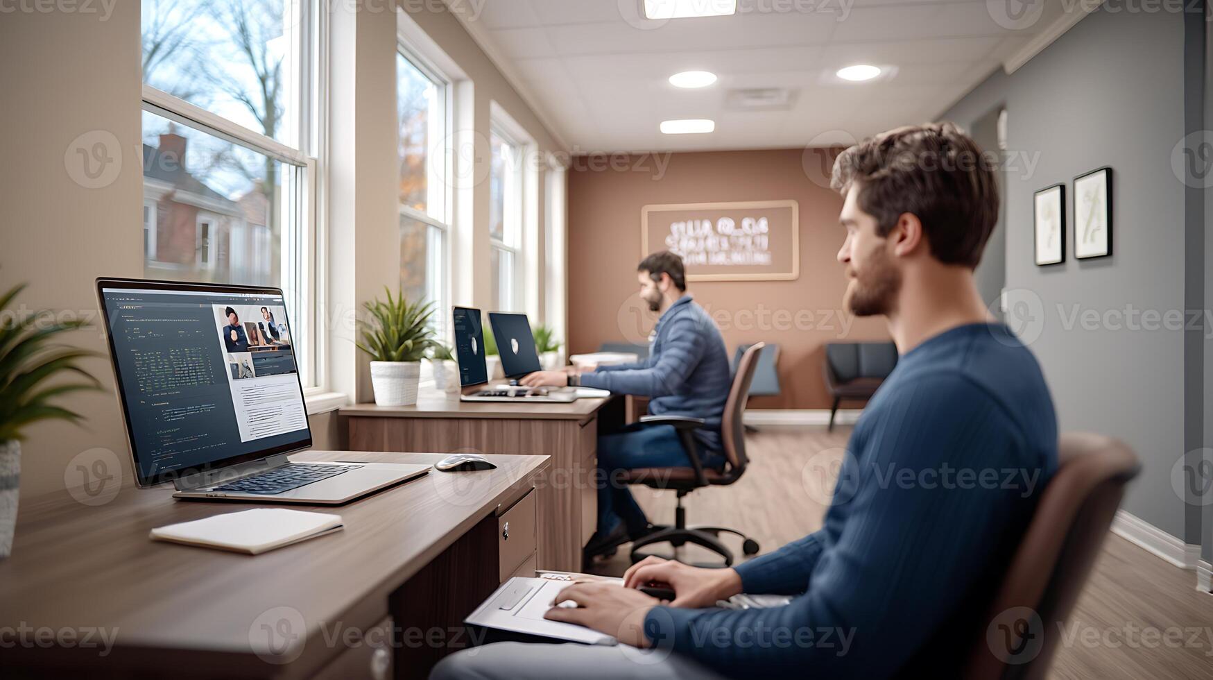 Two men working on computers in a modern office space, focused on tasks with plants around photo