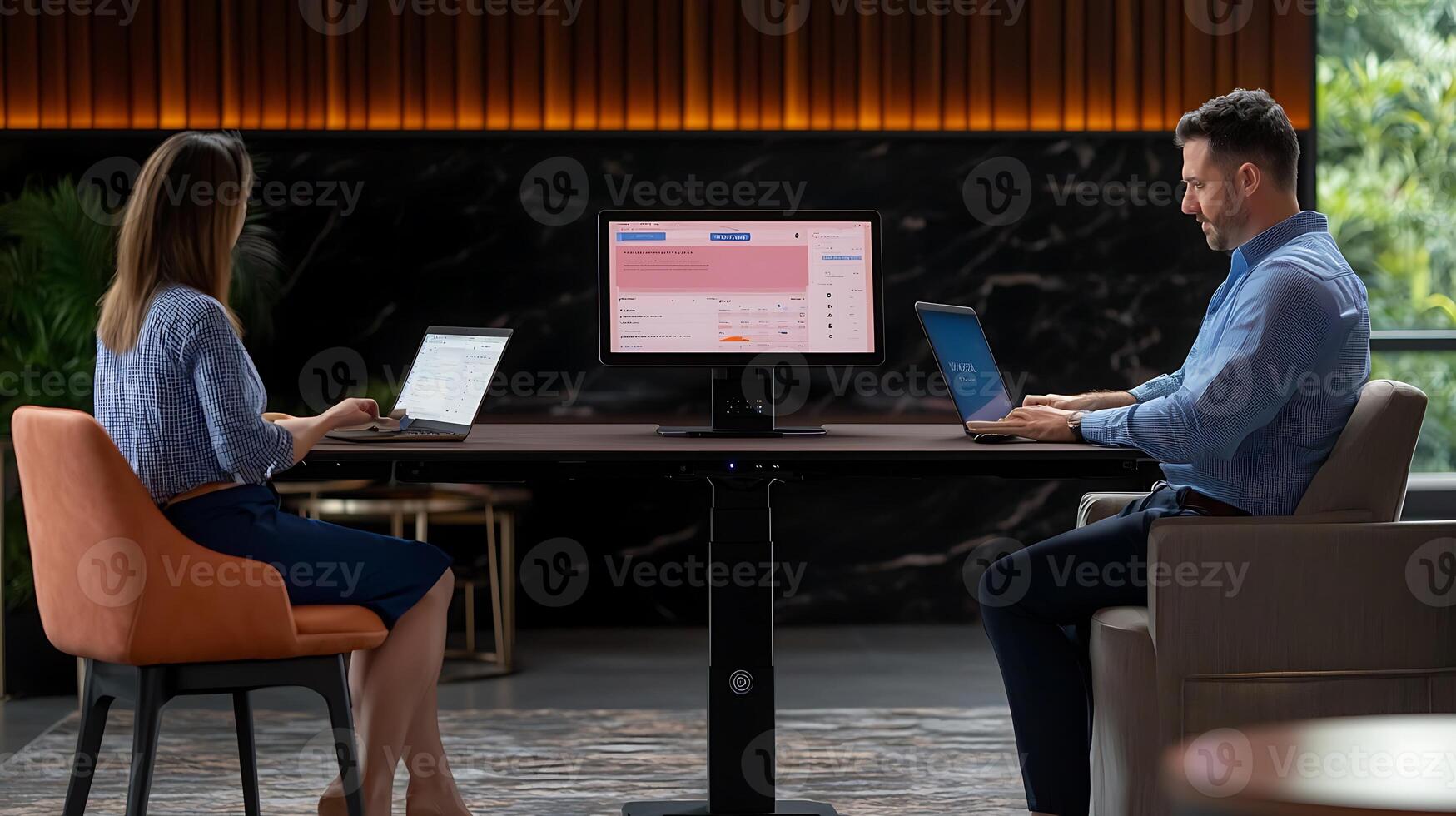 Two professionals working on laptops in a modern office setting with nature in the background photo