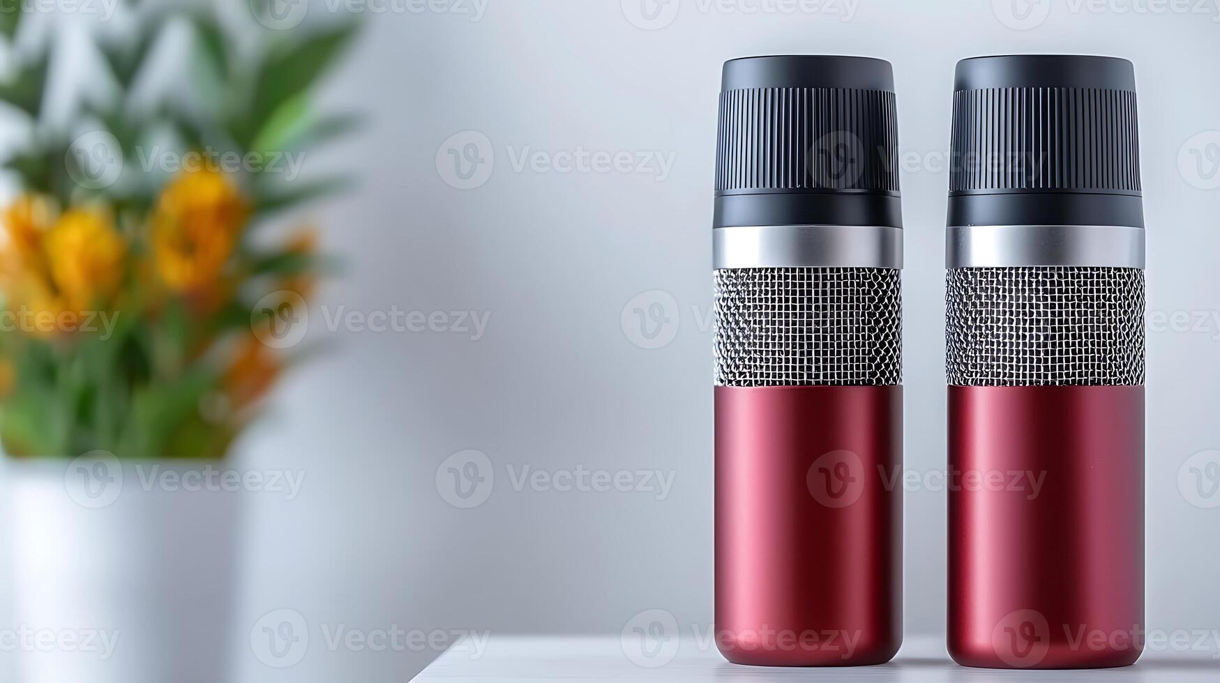 Two stylish red and silver insulated drink bottles on a table with a vibrant floral background photo