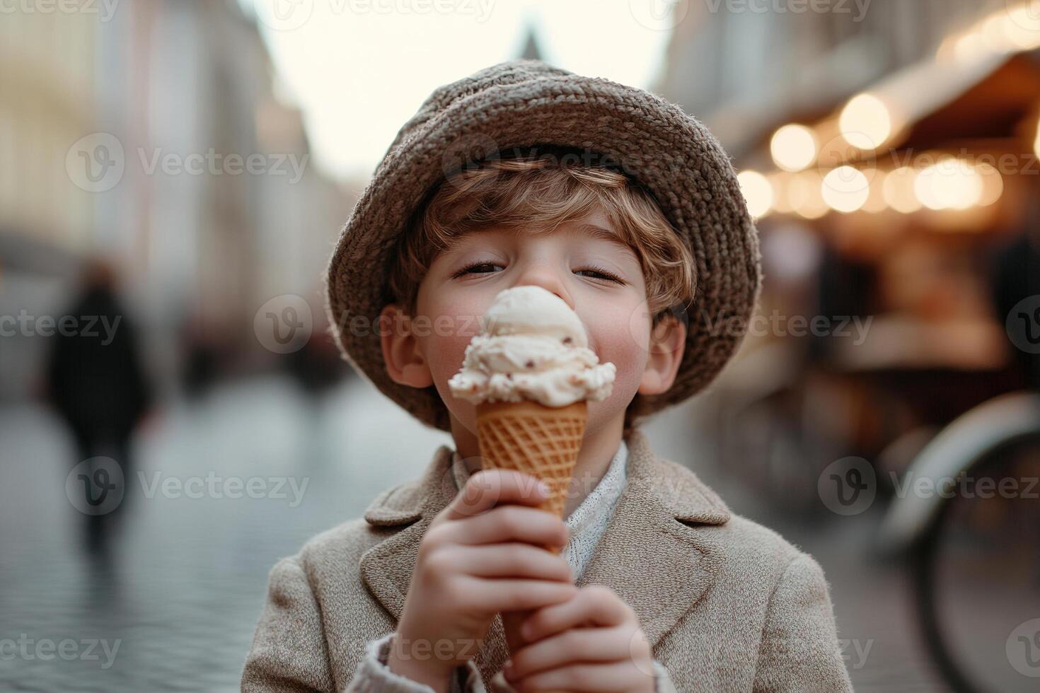 A small child happily licks a melting ice cream cone while standing on a cobblestone street. Softly blurred market stalls and vintage bicycles create a charming backdrop photo
