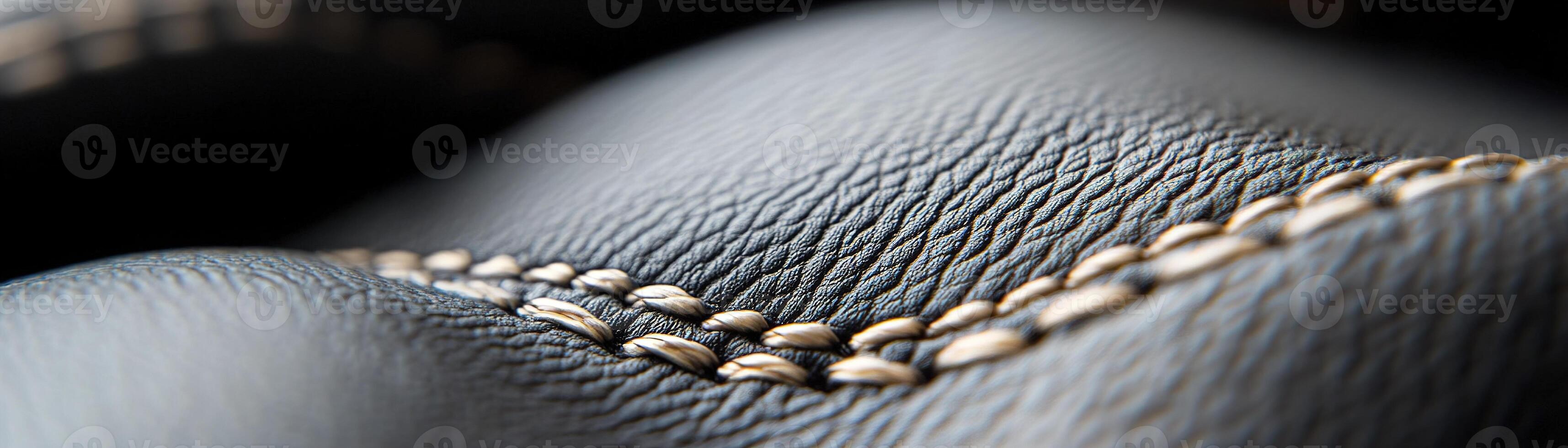 Soft-focus black leather surface features intricate raised stitching that adds a touch of sophistication, making it ideal for luxury branding applications or design projects photo