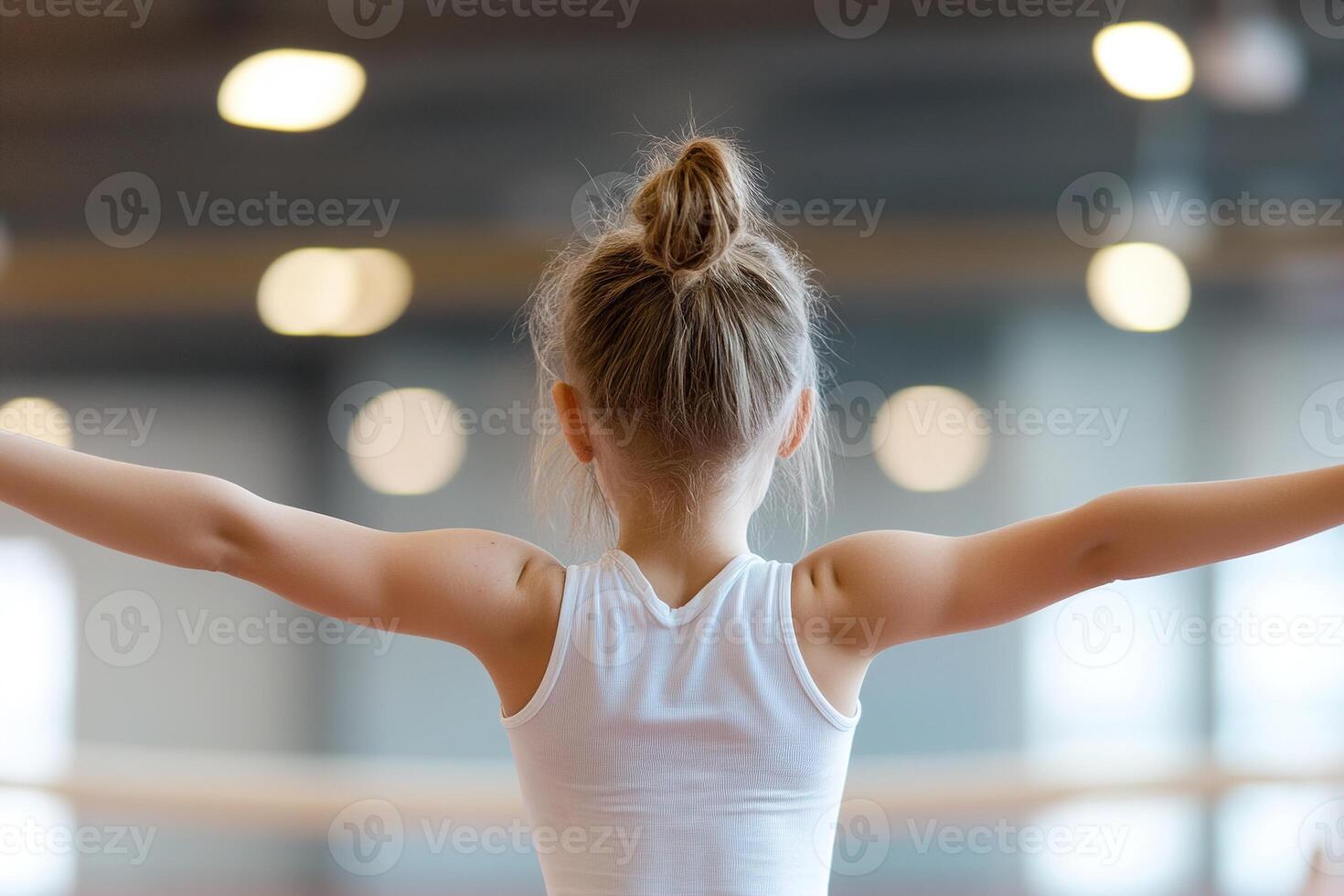 A young girl is focused on balancing on a beam, her arms extended gracefully. The softly lit gym creates an inspiring atmosphere, highlighting her determination and poise photo
