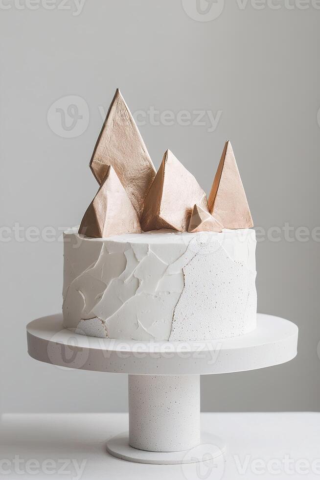This stylish cake showcases a minimalist approach with sharp, angular fondant textures and striking metallic geometric shapes on top, ideal for contemporary celebrations or events photo