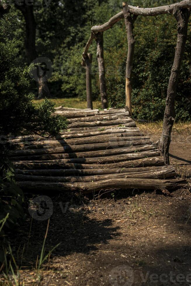wooden bridge made of logs in the forest. huge green trees around. on a sunny day a shadow falls on the path photo