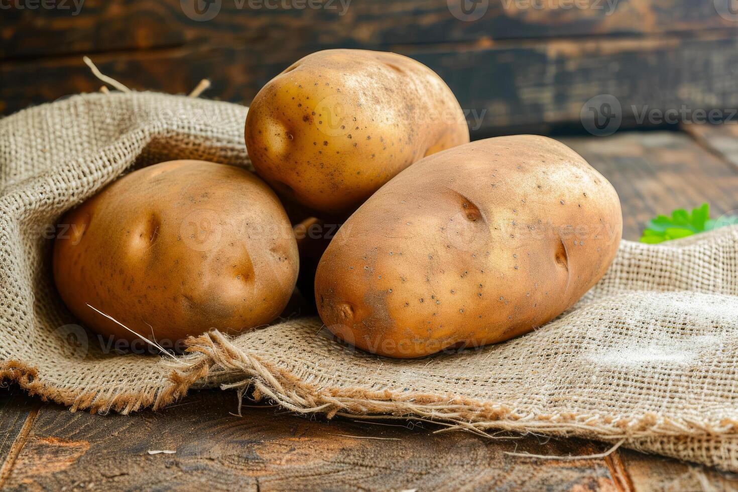 Three potatoes on a sack on a wooden table photo