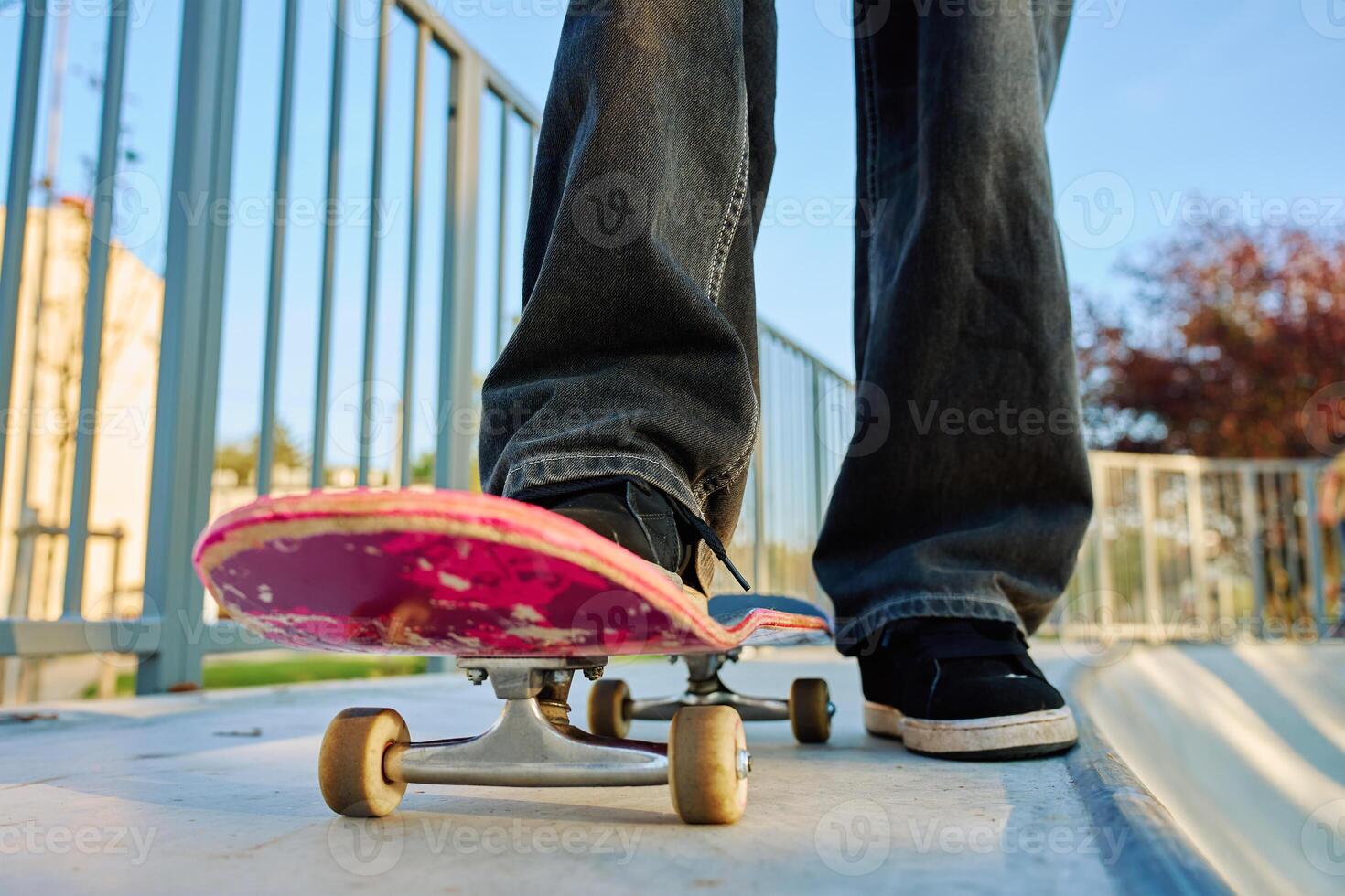 Teenager skateboarder riding on pink skateboard at skatepark photo