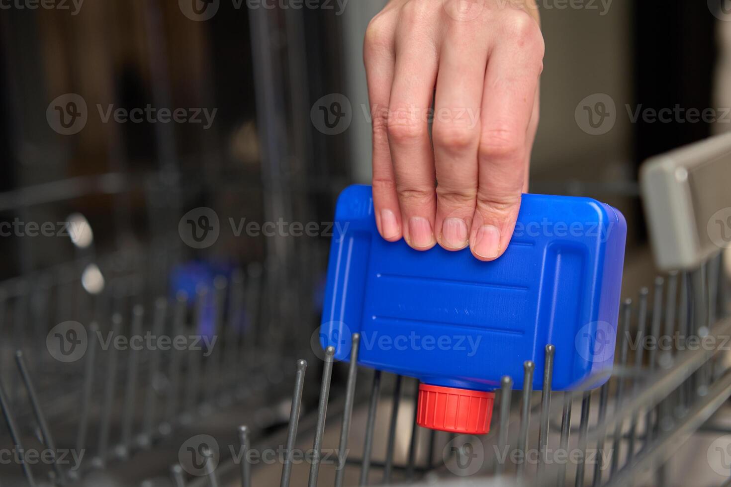 Hand placing dishwasher cleaner bottle in empty dishwasher photo