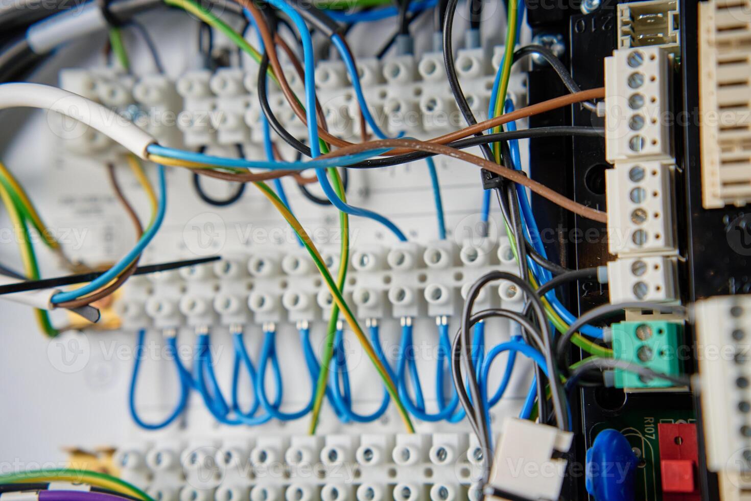 Colorful wires and components connected to terminal block in distribution box. Electrical circuit board with wiring and connections photo