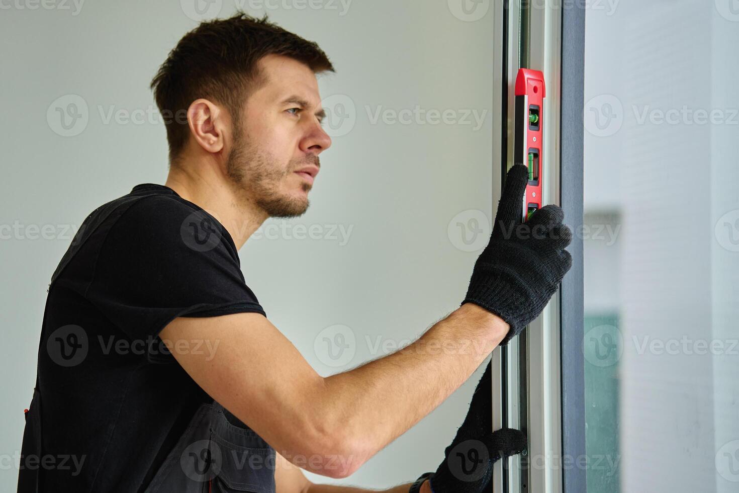 Construction worker checking window level with spirit level during installation photo