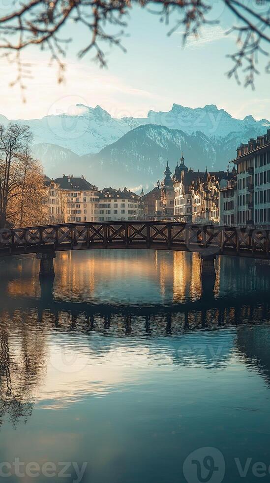 wooden bridge reflecting on the reuss river in lucerne, switzerland, during sunset with mount pilatus in the background photo