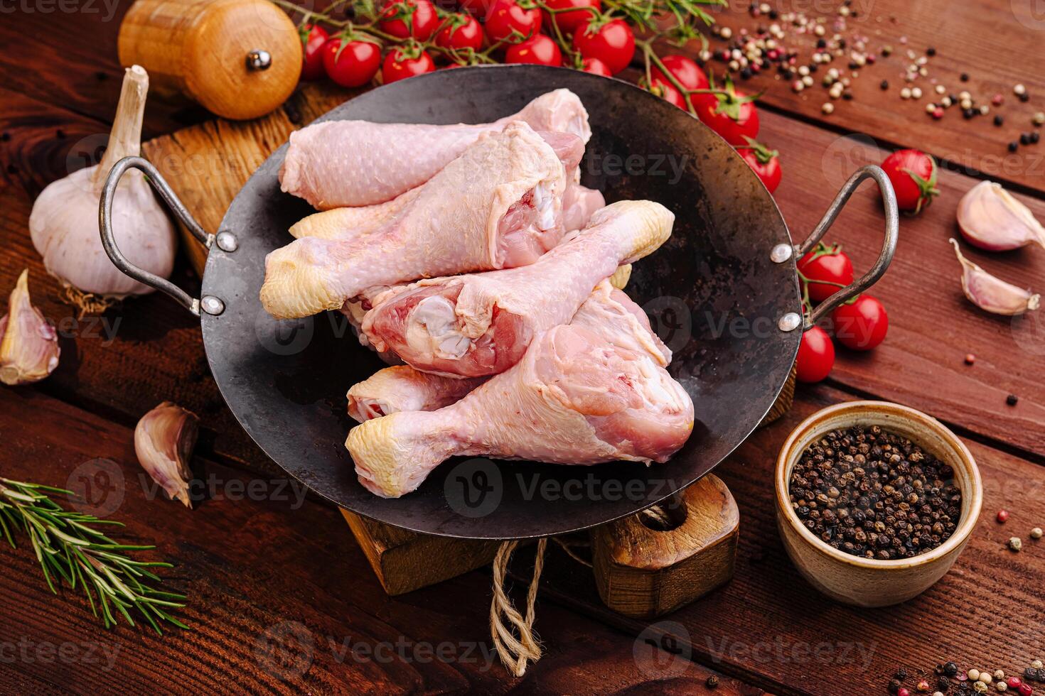 Fresh chicken drumsticks and ingredients arranged on a rustic wooden table in preparation for cooking photo