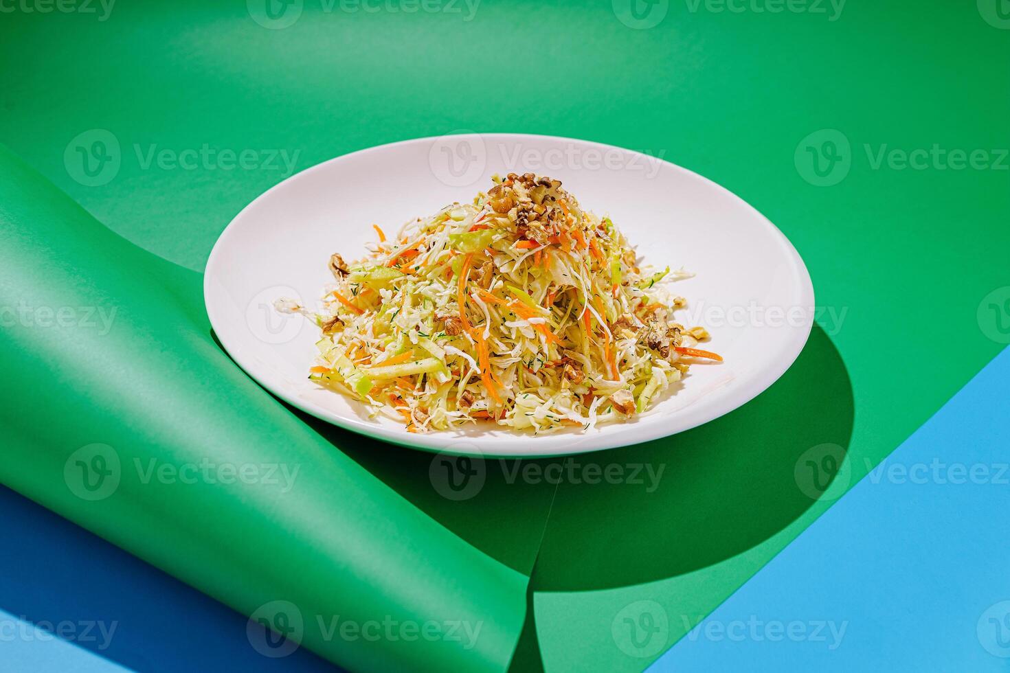 Fresh vegetable salad with colorful ingredients presented on a vibrant green and blue background photo