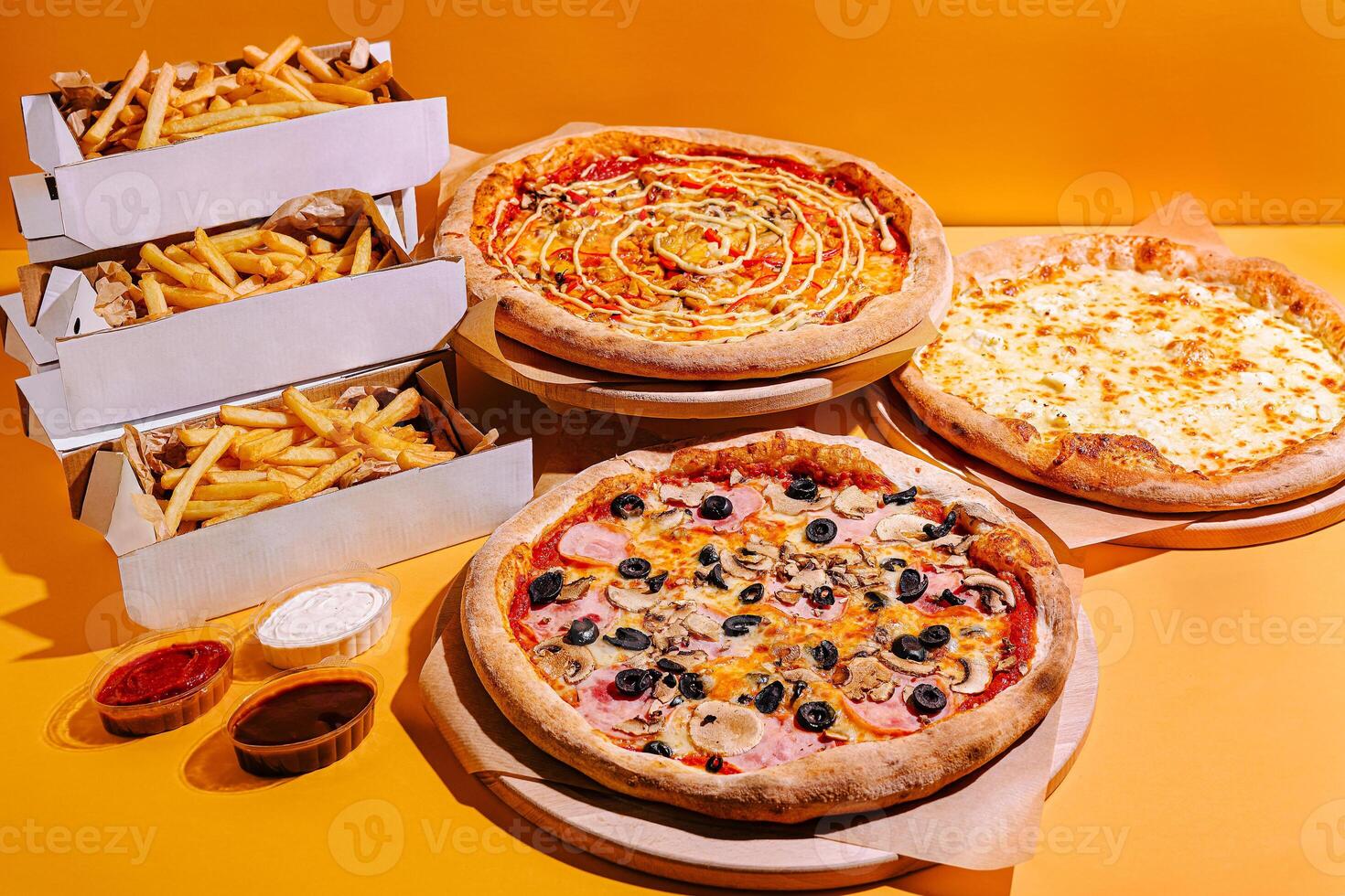 Delicious pizzas and crispy fries displayed on a bright yellow background, perfect for any gathering or celebration photo